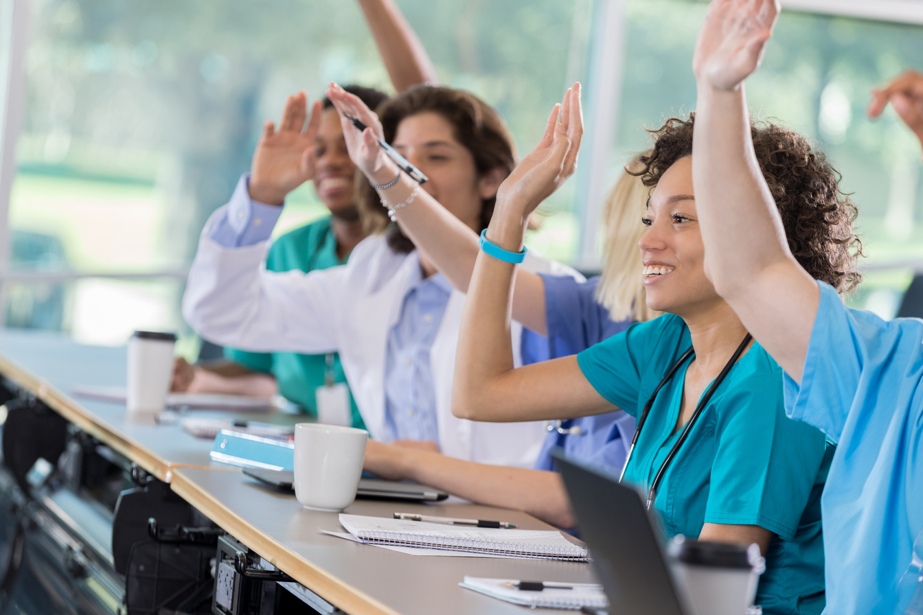 Group of pre-med students raise hands in class